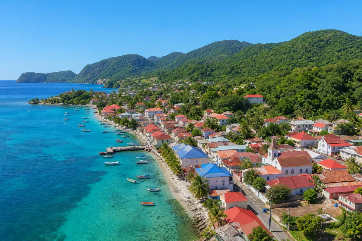Vue sur un village de pêcheurs antillais aux toits colorés, mer et collines vertes en arrière-plan